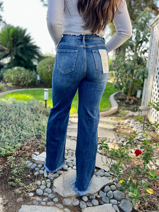 A woman wearing dark high waisted wide leg jeans with boots.