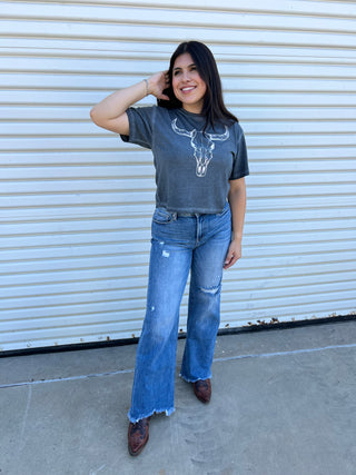 A woman wearing denim wide leg jeans in a high rise with boots.