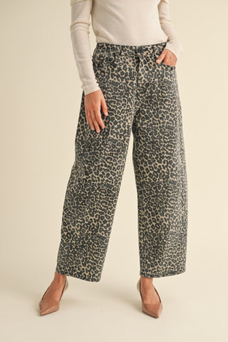 A woman wearing high waisted leopard print barrel leg pants with a light colored top and heels.