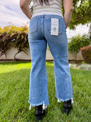 A woman wearing medium wash jeans that are cropped at the bottom.