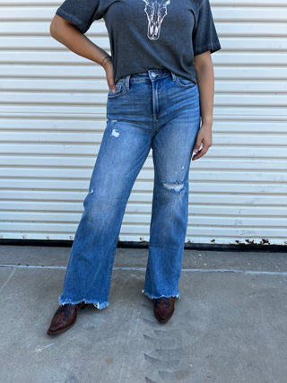A woman wearing denim wide leg jeans in a high rise with boots.
