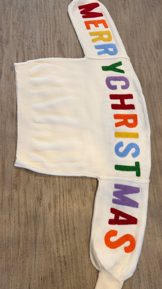 White glove with rainbow-colored 'Merry Christmas' text on a wooden surface