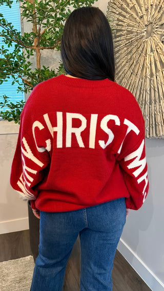 Person wearing a red sweater with 'CHRIST' printed on the back, standing indoors.
