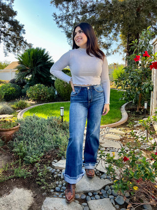 A woman wearing dark high waisted wide leg jeans with boots.