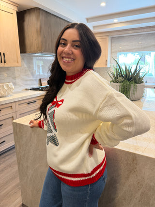 Person wearing a white Christmas sweater with red and blue accents indoors.