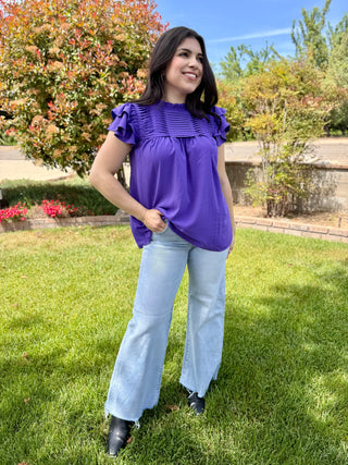 A woman wearing light wash wide leg jeans with a raw hem in a mid rise.