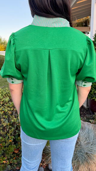 Woman wearing a green blouse with a white collar.