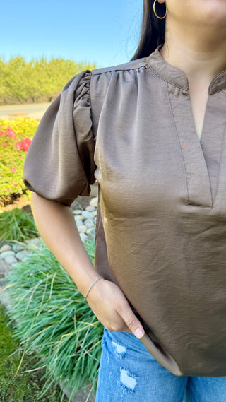 Woman wearing a burgundy V-neck blouse with ruffled sleeves.
