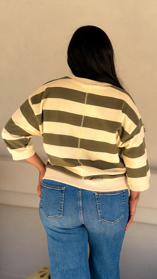Back view of a women's olive and cream striped casual top with dropped shoulders