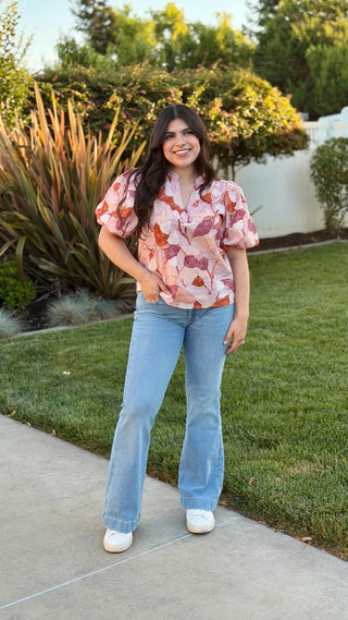 Woman wearing a floral blouse with blue jeans.
