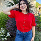 Woman wearing a red shirt and blue jeans standing 