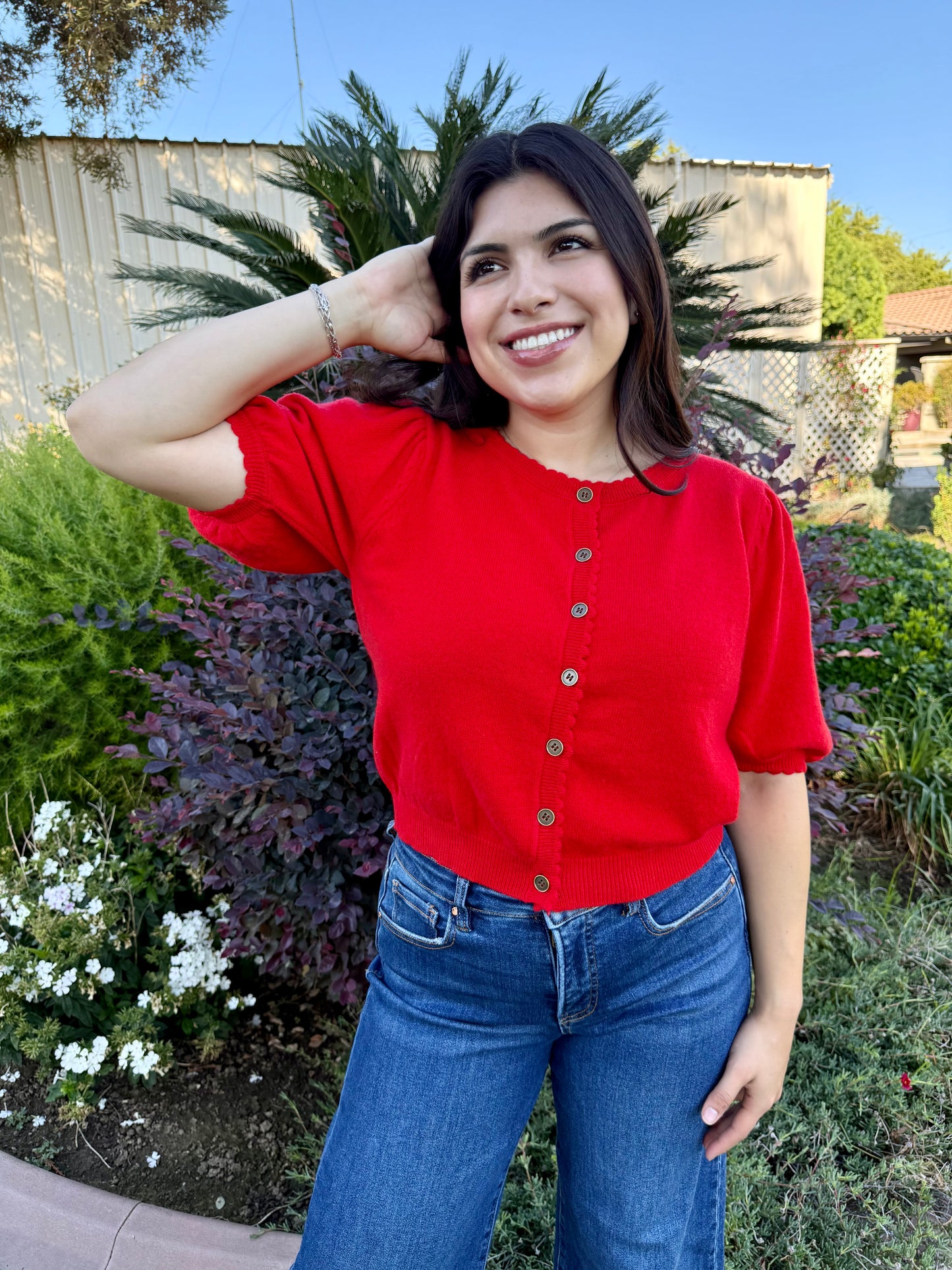 Woman wearing a red shirt and blue jeans standing 