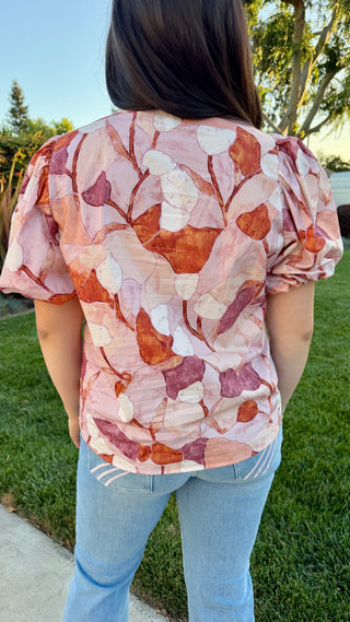 Woman wearing a floral blouse with blue jeans.