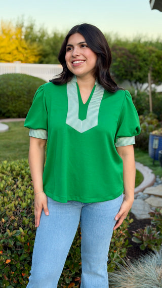Woman wearing a green blouse with a white collar.