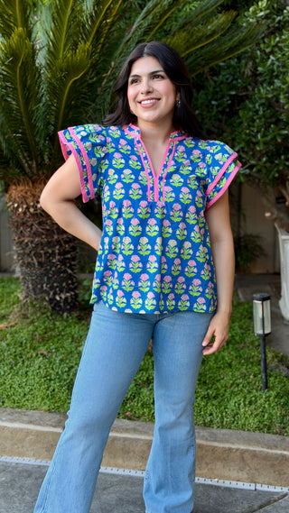 Woman wearing a colorful top with floral pattern and blue jeans.