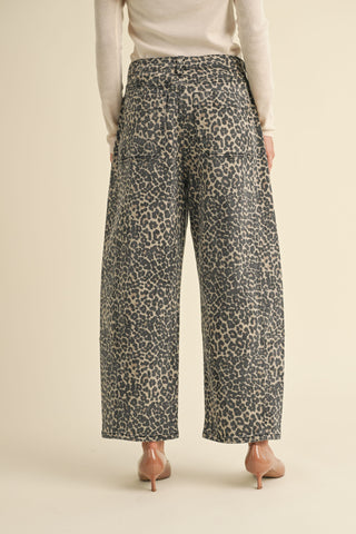 A woman wearing high waisted leopard print barrel leg pants with a light colored top and cowgirl boots. 
