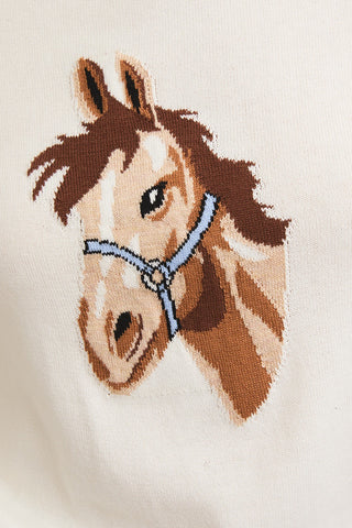 Woman wearing a cream short-sleeve sweater with a horse graphic, paired with leopard-print pants.