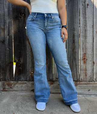A woman wearing light wash jeans with a dark blue stitched 7 on the back pocket. 