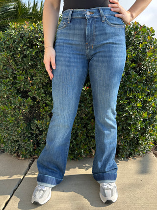A woman wearing dark blue jeans with a red 7 stitched on the back pocket. 