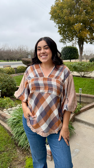 Woman wearing a plaid shirt and jeans standing outdoors.