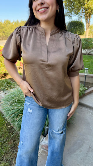 Woman wearing a burgundy v-neck blouse with ruffled sleeves .