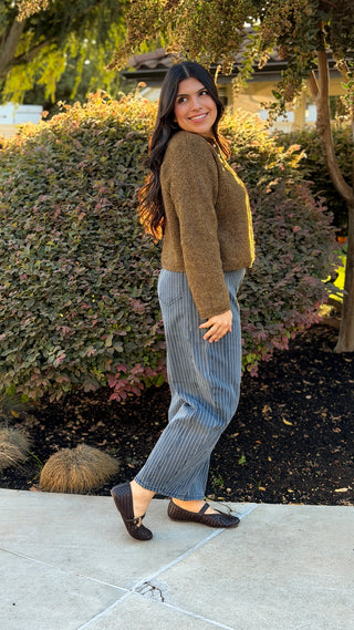 Side view of pinstripe denim barrel pants showing the curved barrel leg shape, worn with a brown cardigan
