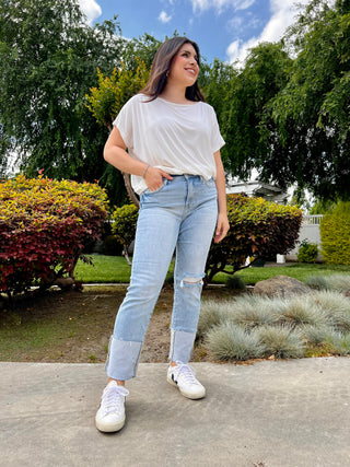 A woman wearing light wash high waisted jeans with a big cuff at the bottom. 