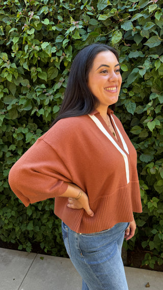 Woman wearing a brown sweater and blue jeans.