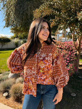 A woman wearing a 3/4 puffer sleeve op with a button down detail and floral pattern. 