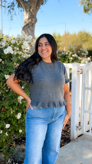 Full-length view of charcoal gray ruffle trim sweater top styled with light blue high rise jeans