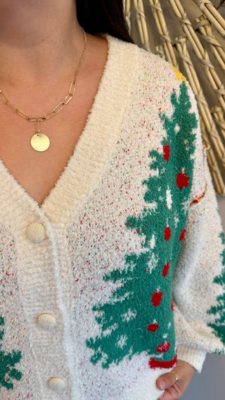 Close-up of a person wearing a cardigan with a Christmas tree pattern.