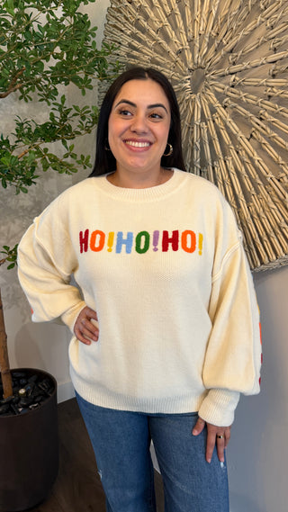 Woman wearing a cream sweater with 'HO! HO! HO!' text in colorful letters
