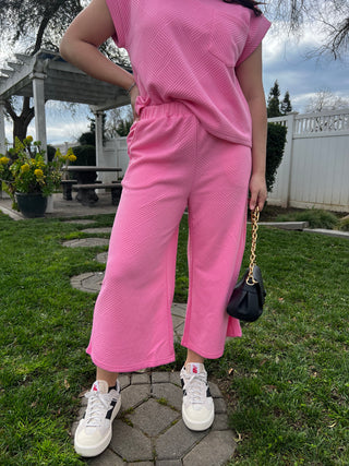 A woman wearing bright pink patterned wide leg cropped pants.