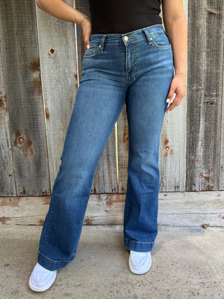 Woman wearing dark wash denim trouser jeans with red, white, and blue stitching on the back pocket