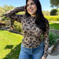 Woman wearing a patterned long-sleeve top and jeans outdoors.
