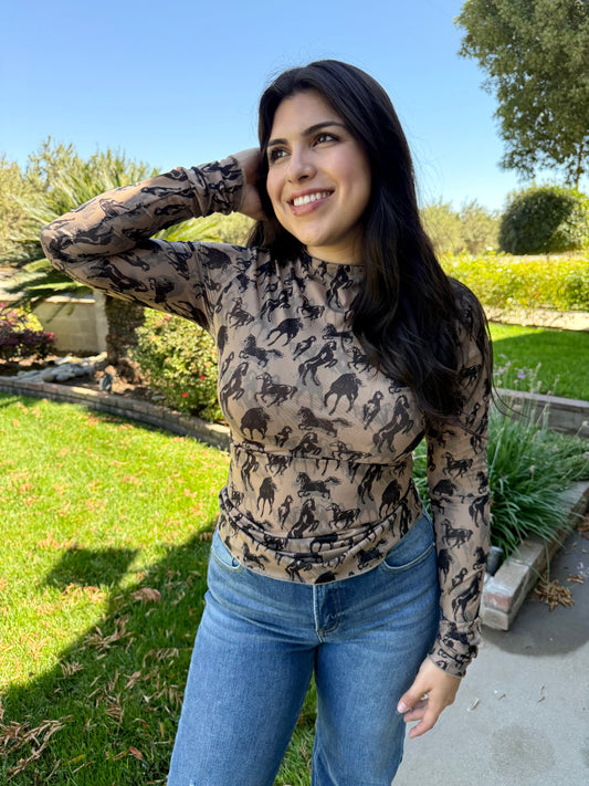 Woman wearing a patterned long-sleeve top and jeans outdoors.