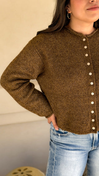 Close-up side view of olive brown ribbed knit cardigan showing the button front and waist-length fit