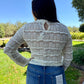 Person wearing a patterned sweater and jeans outdoors on a sunny day
