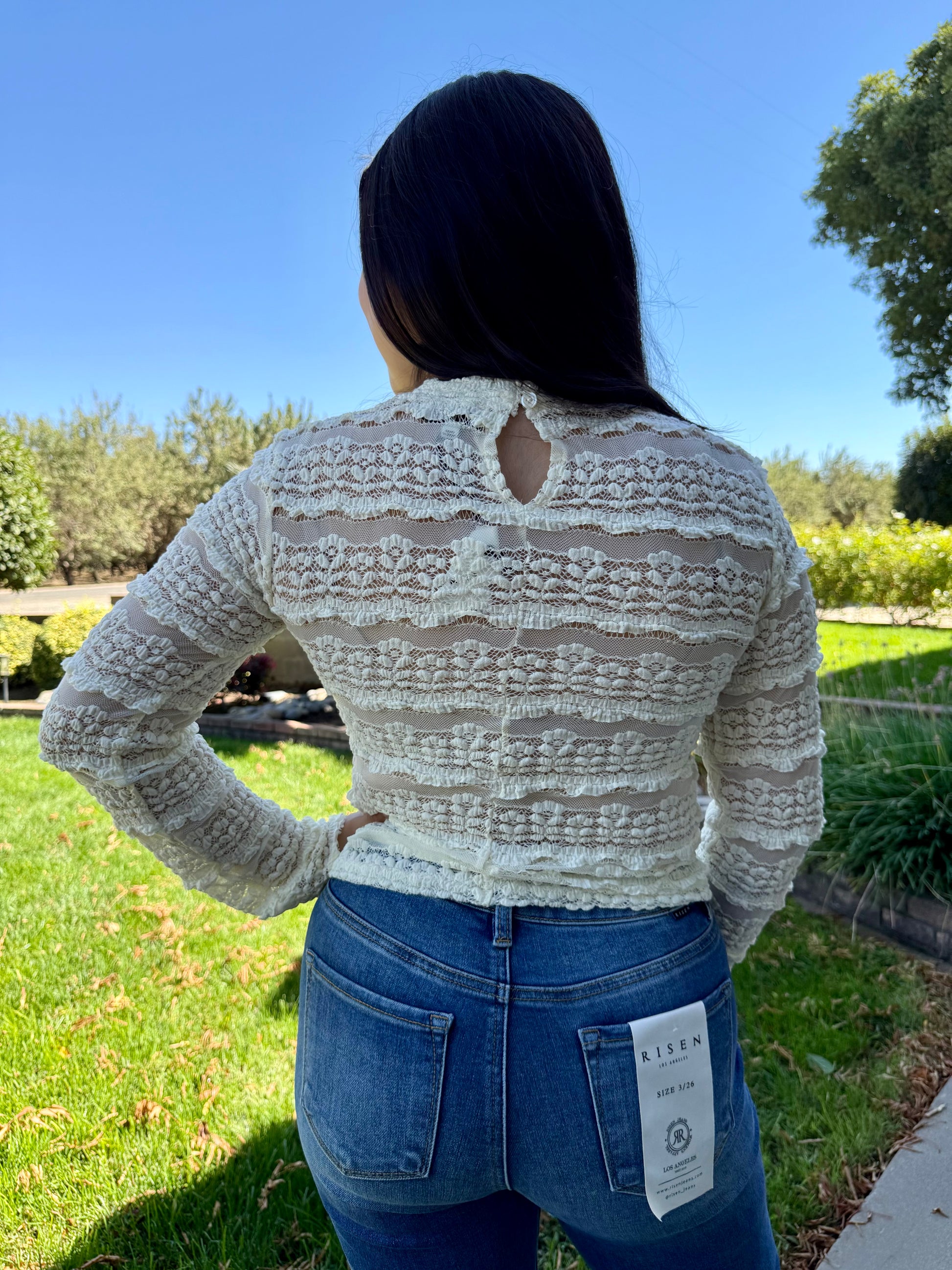 Person wearing a patterned sweater and jeans outdoors on a sunny day