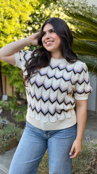 Woman wearing a patterned sweater standing outdoors.