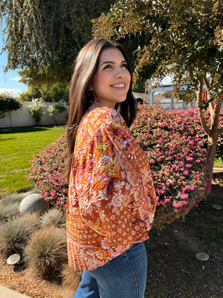 A woman wearing a 3/4 puffer sleeve op with a button down detail and floral pattern. 