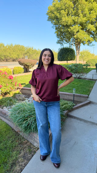 Woman wearing a burgundy v-neck blouse with ruffled sleeves 