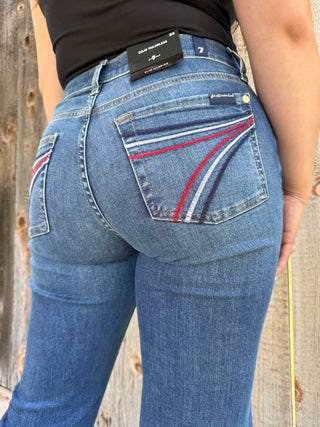 Woman wearing dark wash denim trouser jeans with red, white, and blue stitching on the back pocket