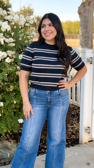Woman wearing navy striped short sleeve sweater knit top with wide leg jeans, front view