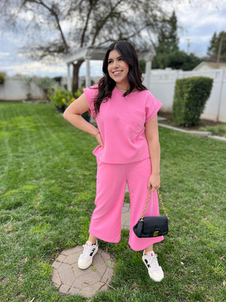 A person wearing pink cropped flare pants with a chevron pattern, standing outdoors.