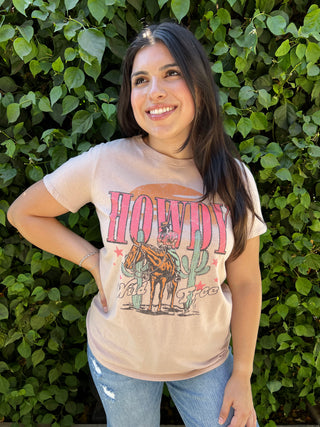 A woman is wearing a t shirt that says howdy on it with a picture of a horse and cactus on it. 