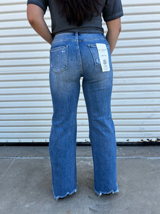 A woman wearing denim wide leg jeans in a high rise with boots. 