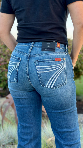 Woman wearing blue jeans with a 7 stitched on pocket.