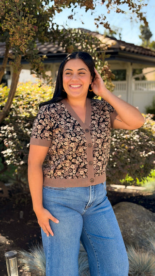 Women's brown floral knit cardigan styled with light-wash jeans outdoors, full-length view