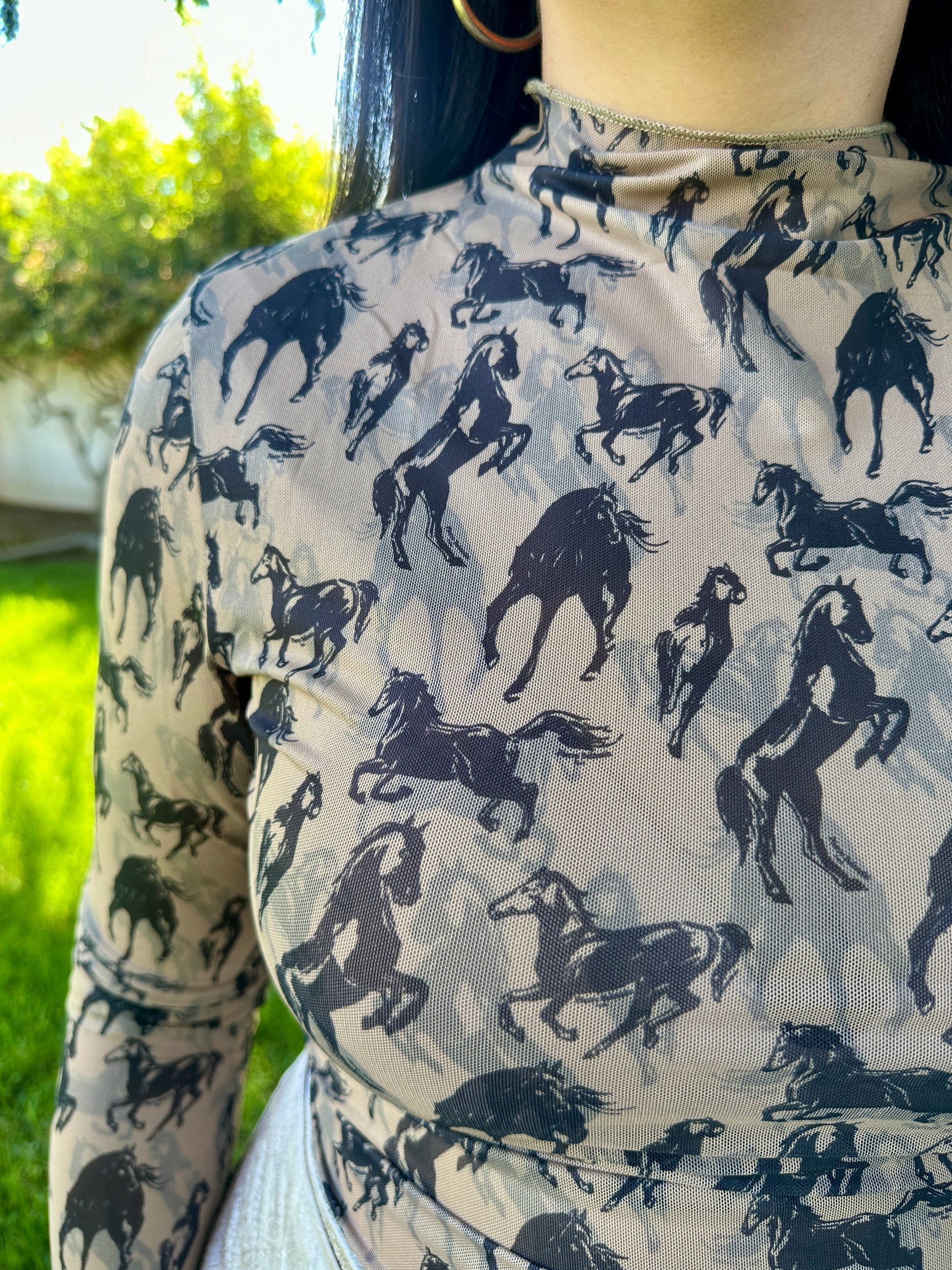 Person wearing a shirt with horse pattern outdoors
